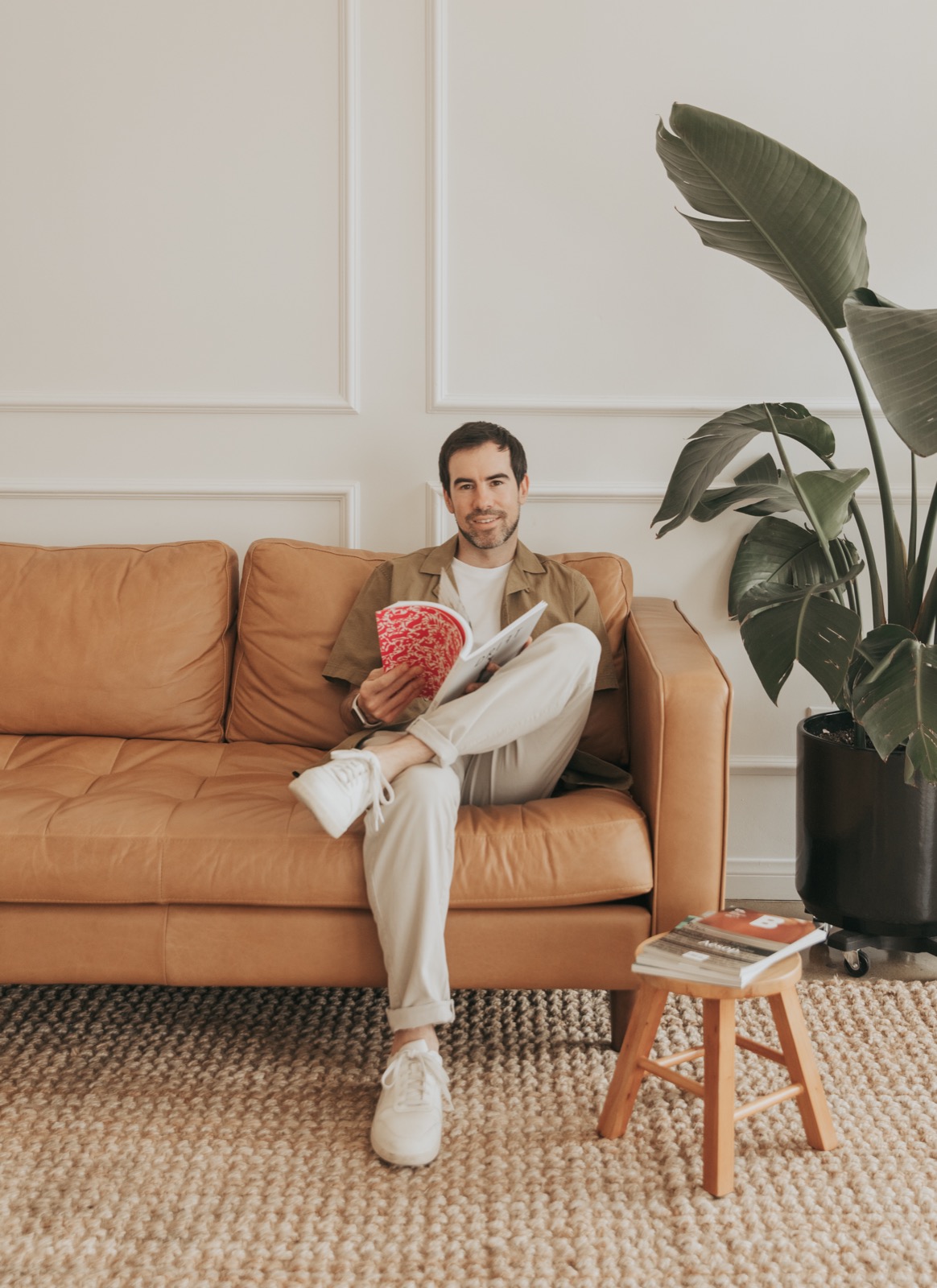 David Sherry sitting on a tan couch with a book